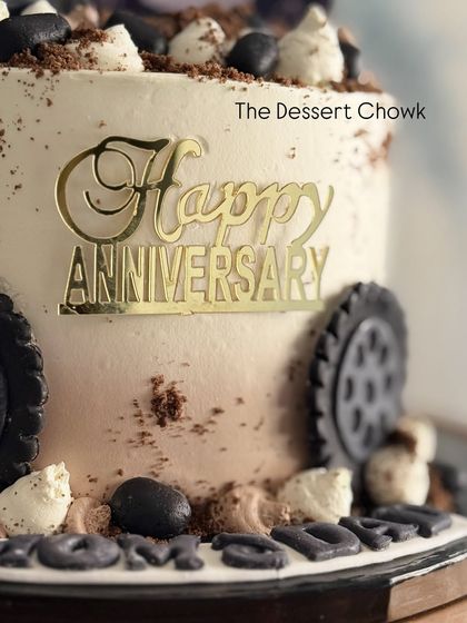 A close-up of the anniversary cake with a Mahindra Thar theme, showing the fondant tires and chocolate crumb "dirt" details.