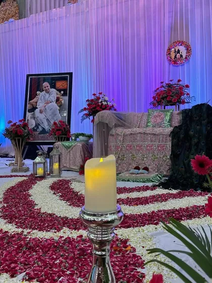 This perspective shows the pathway of devotion we created with flower petals, leading towards the decorated stage. The soft glow from the electric candle adds to the tranquil mood of the satsang.