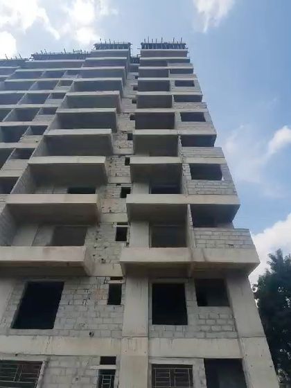 Looking up at the building's facade during construction. This view shows the raw form of the concrete slabs that will eventually become homes.