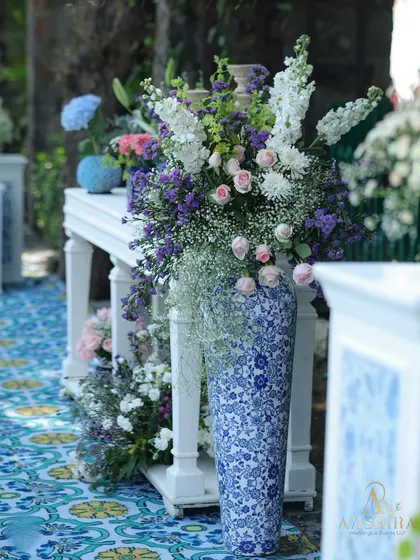A close-up of the decor, featuring a large blue and white patterned vase holding a lush arrangement of white, pink, and purple flowers, set on a tiled floor.