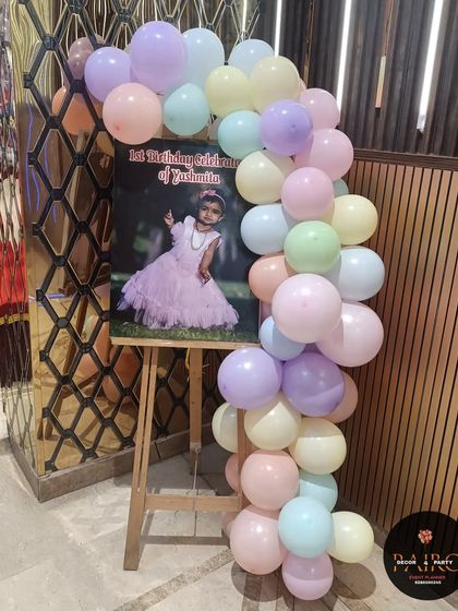 A personalized welcome easel for a mermaid-themed party, framed with matching pastel balloons.