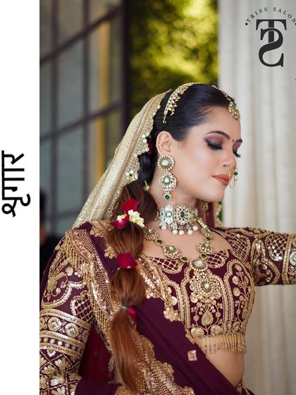 This image captures the side profile, highlighting the intricate hairstyle with floral details that complements the rich, traditional bridal attire and makeup.