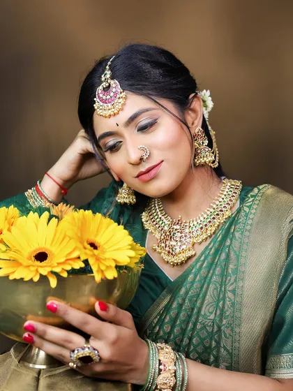 The model's serene expression captures the festive spirit. The jewellery, including the choker, jhumkas, and nose ring, are all available for rent.