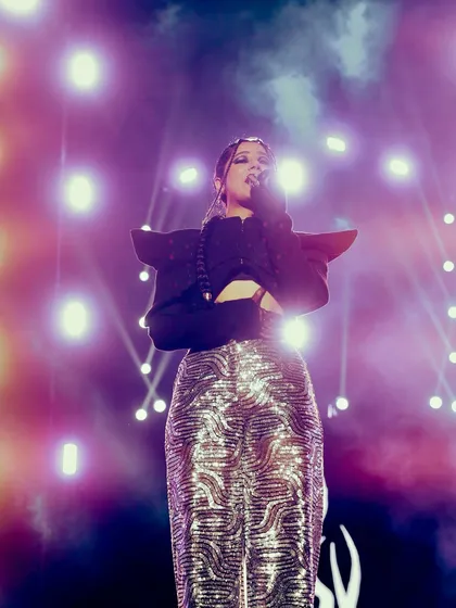 A full-length shot of Agsyworld, highlighting her stage presence and outfit against a backdrop of brilliant lights. Capturing the artist's complete look is key for performance photography.