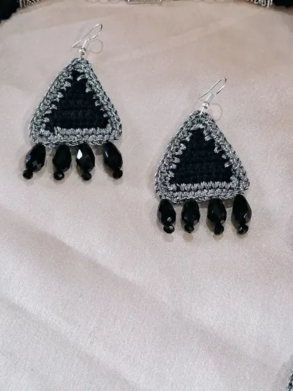 A close-up of the triangular crochet earrings, part of a custom set. The black beads add a touch of elegance and tie the design together with the matching necklace.