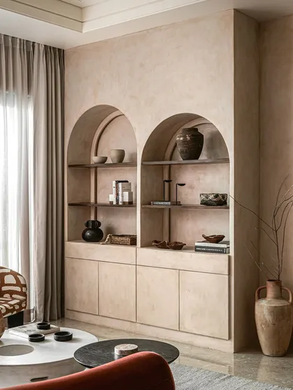 This feature wall in the living room includes custom arched niches for displaying decor. The entire unit is finished in the same lime wash as the walls, creating a seamless, sculptural look that is both beautiful and functional.
