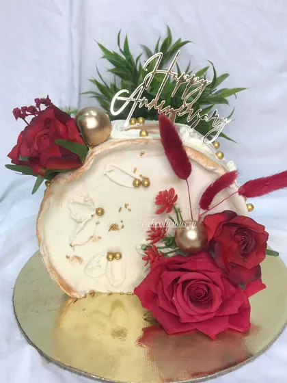 A top-forward cake designed for an anniversary. The combination of red, white, and gold is timeless. This chocolate mousse cake is finished with white ganache, a fault line design, and decorated with rich red roses.