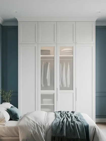 A floor-to-ceiling built-in wardrobe in a classic shaker style, painted in a calming blue-grey. The design includes frosted glass doors in the center, offering a glimpse of the organized interior with integrated lighting.