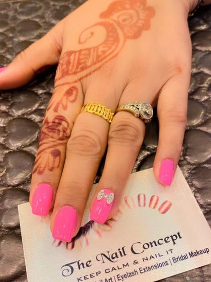 A fun and simple design on short, square nails. The bright pink polish is accented with a single 3D rhinestone bow on the ring finger.