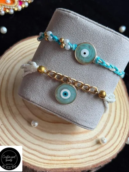 Ward off negativity with this stylish evil eye Rakhi set. The modern design combines the protective charm with a gold chain for the bhabhi and a simple thread for the bhaiya.