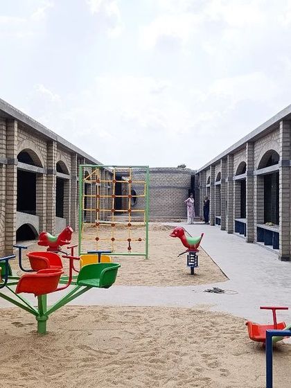 A wide view of the play area at Sai Kirupa, flanked by the adobe block classrooms. The entire campus is designed with principles of inclusive and sensory architecture to support the school's educational mission.