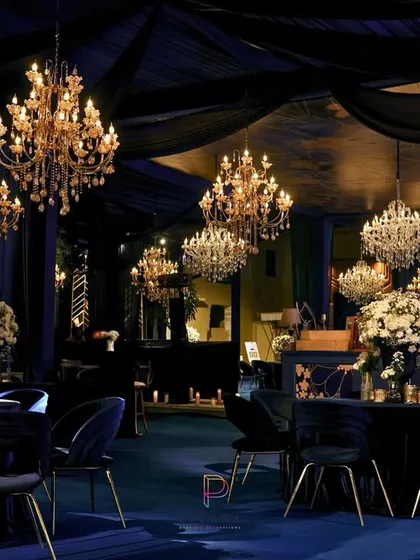 We set a moody and majestic tone for this evening reception with a deep blue and gold color palette. The space is draped in midnight fabrics, with crystal chandeliers casting a warm glow over velvet chairs and tables dressed in white florals.