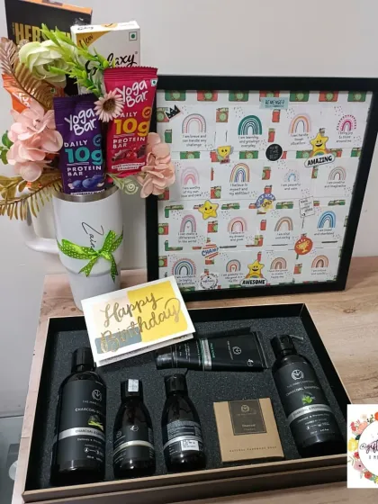 A birthday hamper combining wellness and motivation. It features an affirmation quote frame, a Stanley mug bouquet with protein bars, and a men's grooming kit.