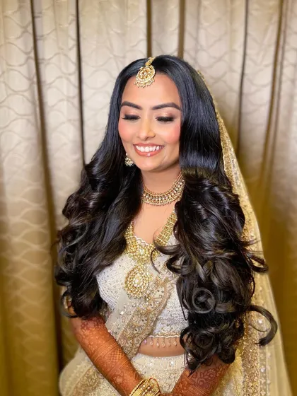 Bansi's joyful smile lights up the room. Her makeup is natural and radiant, perfect for her elegant white lehenga.