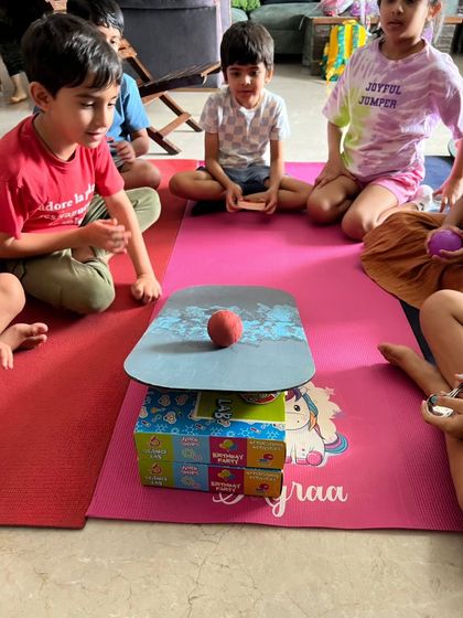 A group of kids intently watching an experiment about balance and center of gravity. Every moment is a learning opportunity.
