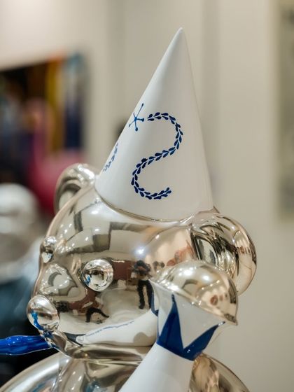 The party hat of the silver "Let's Party Teddy," with its delicate blue-and-white pattern, sits atop the gleaming chrome head.
