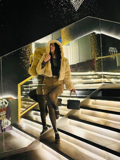 A full-length shot walking down the stairs, showing the movement and flow of the outfit.