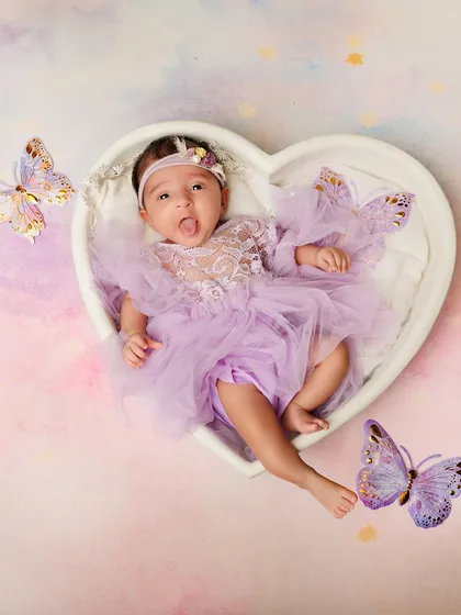 This little butterfly is sticking her tongue out! A playful and adorable moment captured in a heart-shaped bowl with a pastel butterfly theme.