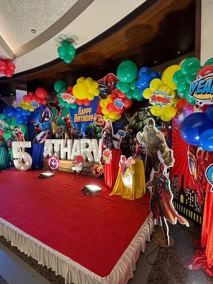 The entire party area is themed, with colorful balloon columns and props extending beyond the main stage to decorate the whole venue.