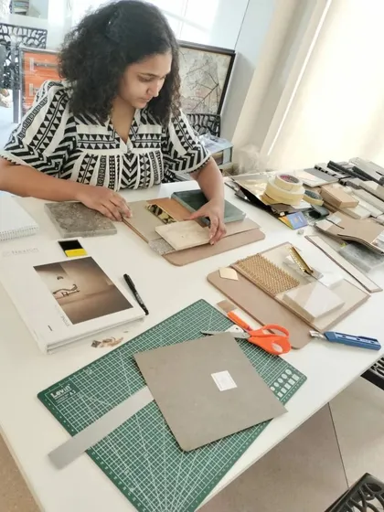 A designer at work, organizing material samples for a mood board. This hands-on process is essential for ensuring textures, colors, and finishes work together harmoniously.