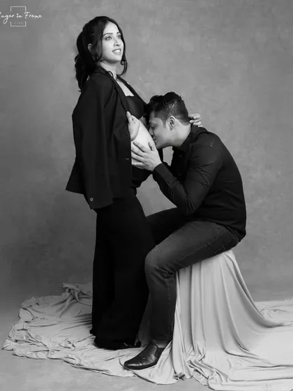 A tender and modern black and white portrait. The father-to-be gently kisses the baby bump, creating a timeless and intimate memory of this special time.