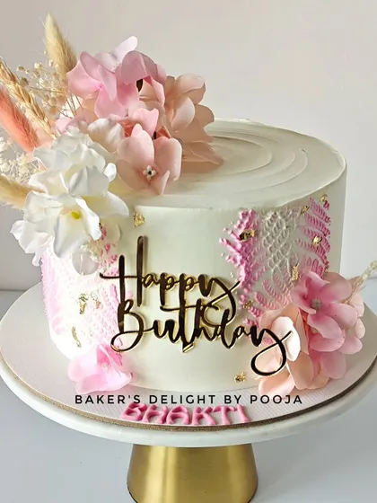 A pretty pink and white stenciled cake decorated with delicate dried and artificial flowers. The vanilla and mixed seasonal fruit flavor is as fresh as the design.
