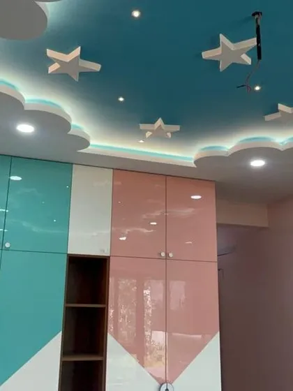 A glimpse of a kids' bedroom we designed. We created a playful atmosphere with a custom cloud-and-star false ceiling and a two-tone wardrobe that provides ample storage.
