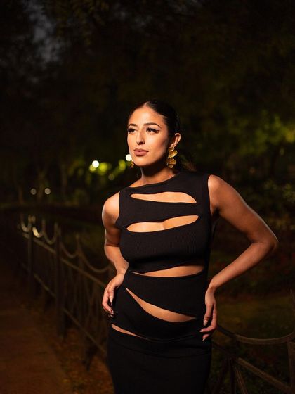 A powerful pose in a night-time setting. The direct lighting illuminates the model and the details of her cut-out dress, creating a bold and glamorous look.