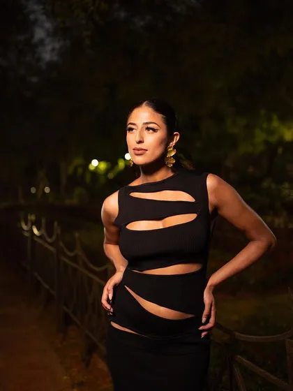 A powerful pose in a night-time setting. The direct lighting illuminates the model and the details of her cut-out dress, creating a bold and glamorous look.