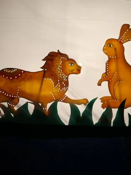 A classic moment from a Panchatantra tale, where the clever rabbit confronts the mighty lion. The detail in these leather puppets is stunning, and they create such powerful silhouettes during the shadow puppet performance.