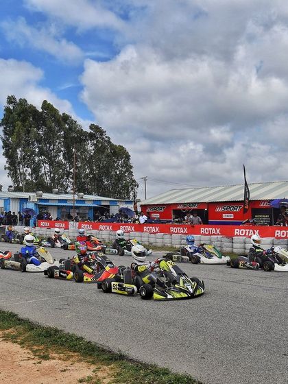 The grid forms up for a race start at Meco Kartopia, with the pit buildings in the background.