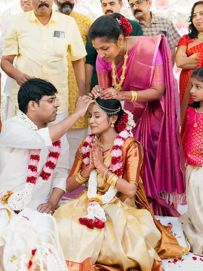 A significant ritual from a South Indian wedding, captured with family looking on.