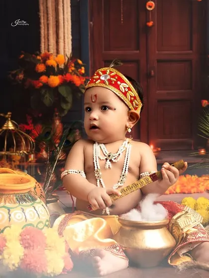 This baby looks so curious in his Krishna costume, sitting amidst a colorful setup with smoke effects coming from a pot of 'butter'.