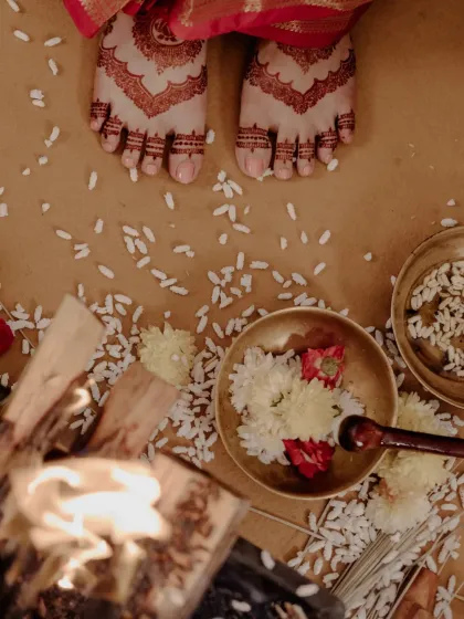 An artistic top-down view of the bride's feet, adorned with a beautiful henna stain, during a traditional ceremony.