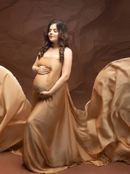 Golden hues for a golden time. The flowing, shimmering fabric catches the light beautifully, celebrating the radiant glow of motherhood.