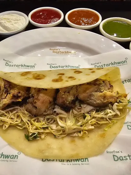 A classic Chicken Tikka Roll, filled with tender tandoori chicken tikka and crisp shredded cabbage, served with a variety of chutneys and sauces.