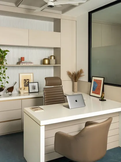 The MD cabin is a showcase of refined detail, with a fluted texture behind the shelving and a clean, organized workspace. The design combines storage and display within a sophisticated beige and brown palette.