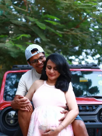 A happy and relaxed portrait of the couple posing with their car, showing their casual and fun-loving personalities.