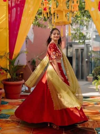 A happy client twirling in her vibrant red and lime green lehenga. The floral embroidered blouse and flowing skirt make this a perfect outfit for a Haldi or Mehendi function.