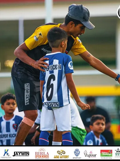 A coach gives tactical instructions to a young player during a break in play.