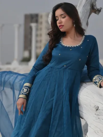 A deep teal Anarkali suit with embroidered cuffs and a sheer dupatta. This elegant ensemble is perfect for evening events and formal gatherings.