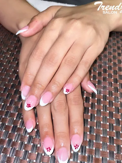 I love adding a personal touch to a classic design. Here, I've enhanced a traditional French manicure with a tiny, hand-painted red flower on the accent nail for a subtle pop of color and detail.