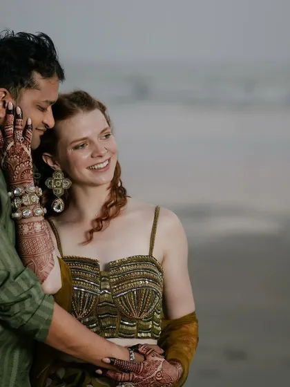An intimate moment between the couple. The groom's sheer olive kurta and the bride's embellished top create a beautifully textured, coordinated look.