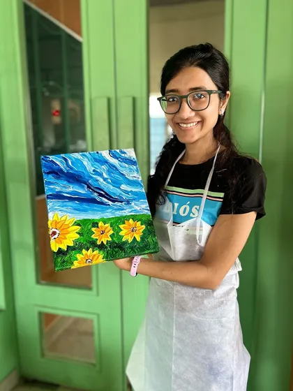A proud artist holding her vibrant sunflower landscape painting. It's always a joy to see what our participants create.
