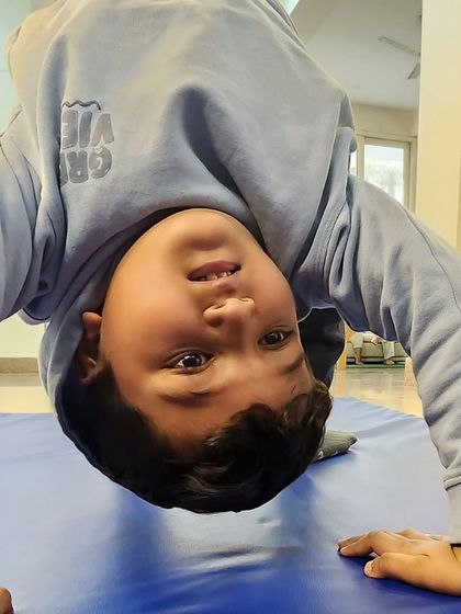 A different perspective. This young gymnast is practicing a bridge, building back flexibility and arm strength. This upside-down view shows his confidence and progress.