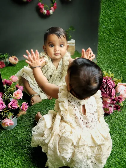 A baby discovers her reflection in the mirror. Using props like mirrors can lead to fascinating and adorable moments of self-discovery during a shoot.