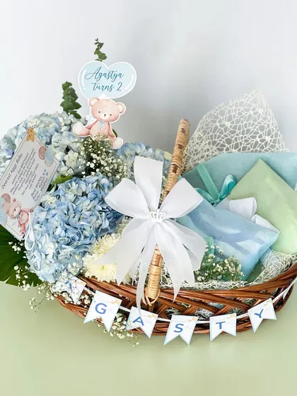 This charming basket for Agastya's second birthday is filled with blue hydrangeas and thoughtful gifts. The personalized banner adds a special touch to the celebration.