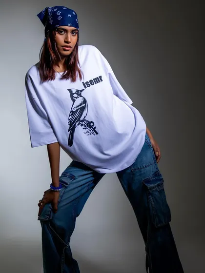 A full-body shot of a model styled in an oversized graphic tee, baggy jeans, and a bandana. This look captures a classic 90s hip-hop vibe, tailored for a modern streetwear brand.