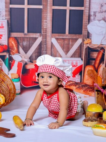 This baby is having a great time exploring our master chef setup. The variety of props, from bread to donuts, makes for a visually rich and playful photoshoot.