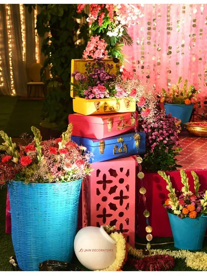 A collection of colorful props, including painted baskets and vintage-style suitcases filled with flowers. These elements add layers of color and interest to the decor.
